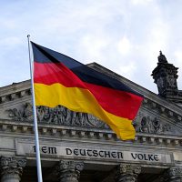 German national flag waving in front of the Reichstag building in Berlin, a symbol of democracy.